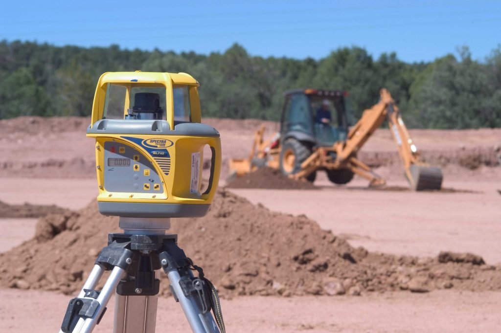 Laser level and excavator showing construction workflows automation in earthmoving.
