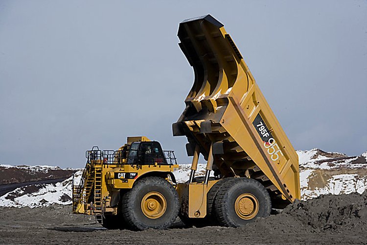 Mining haul truck unloading material on site, enhanced with loadrite retrofits for accurate payload measurement and improved fleet efficiency.