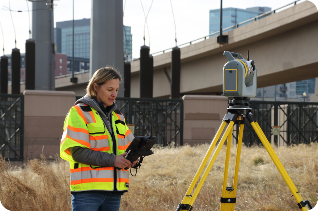 Spectra vs Trimble surveying equipment in use on a construction site with surveyor operating a total station and data controller.